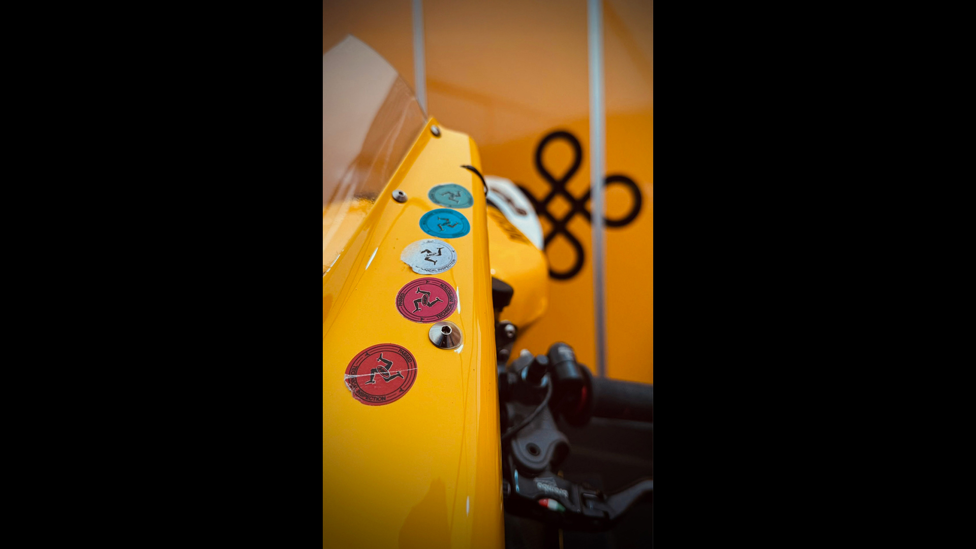 Mototbike windsheild showing Isle of Man stickers and prosperity logo in the background